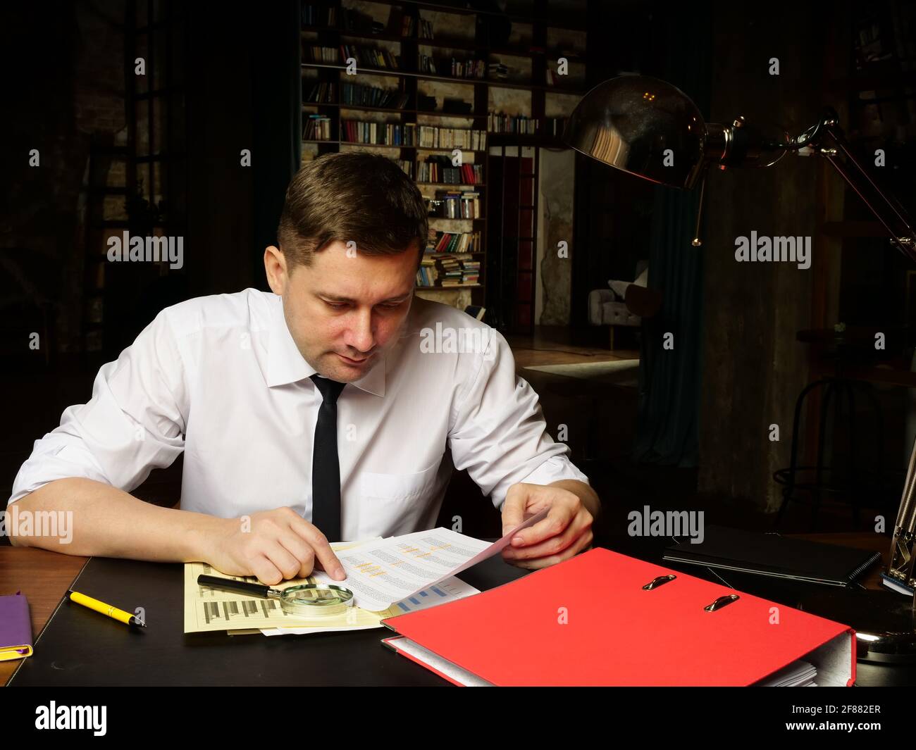 The auditor works late with the report and financial data. Stock Photo