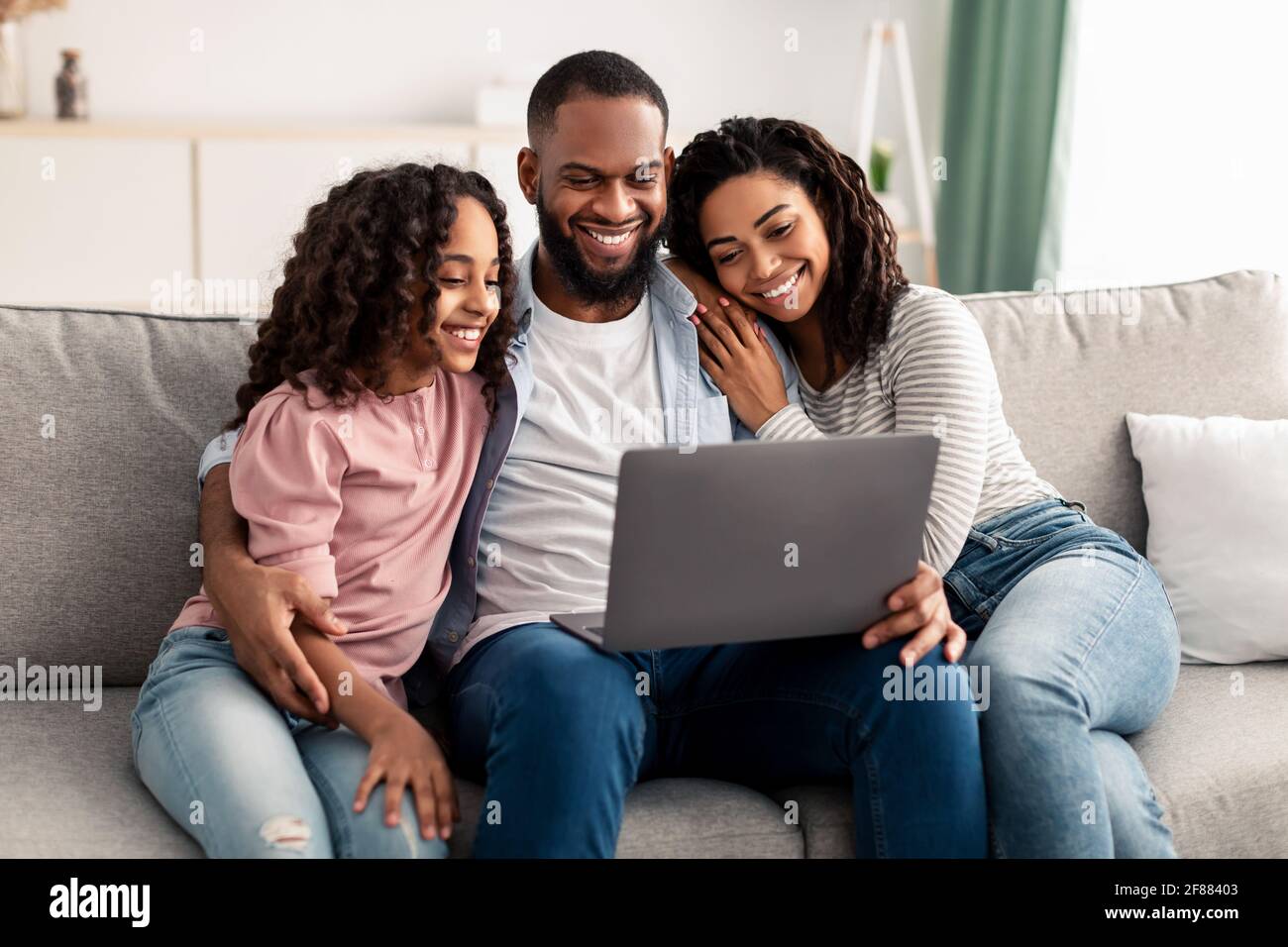 Happy afro family using laptop sitting on the couch Stock Photo - Alamy