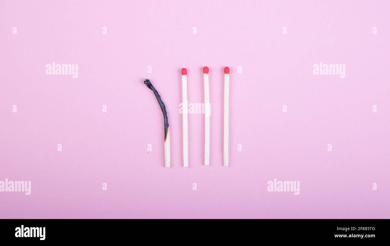 four match sticks, one burned on pink background Stock Photo