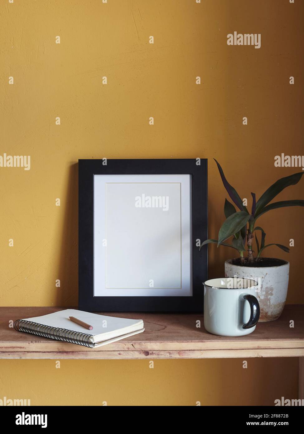 Wooden frame mockup. Composition with a flowerpot, a notebook . Against the background of a yellow wall Stock Photo