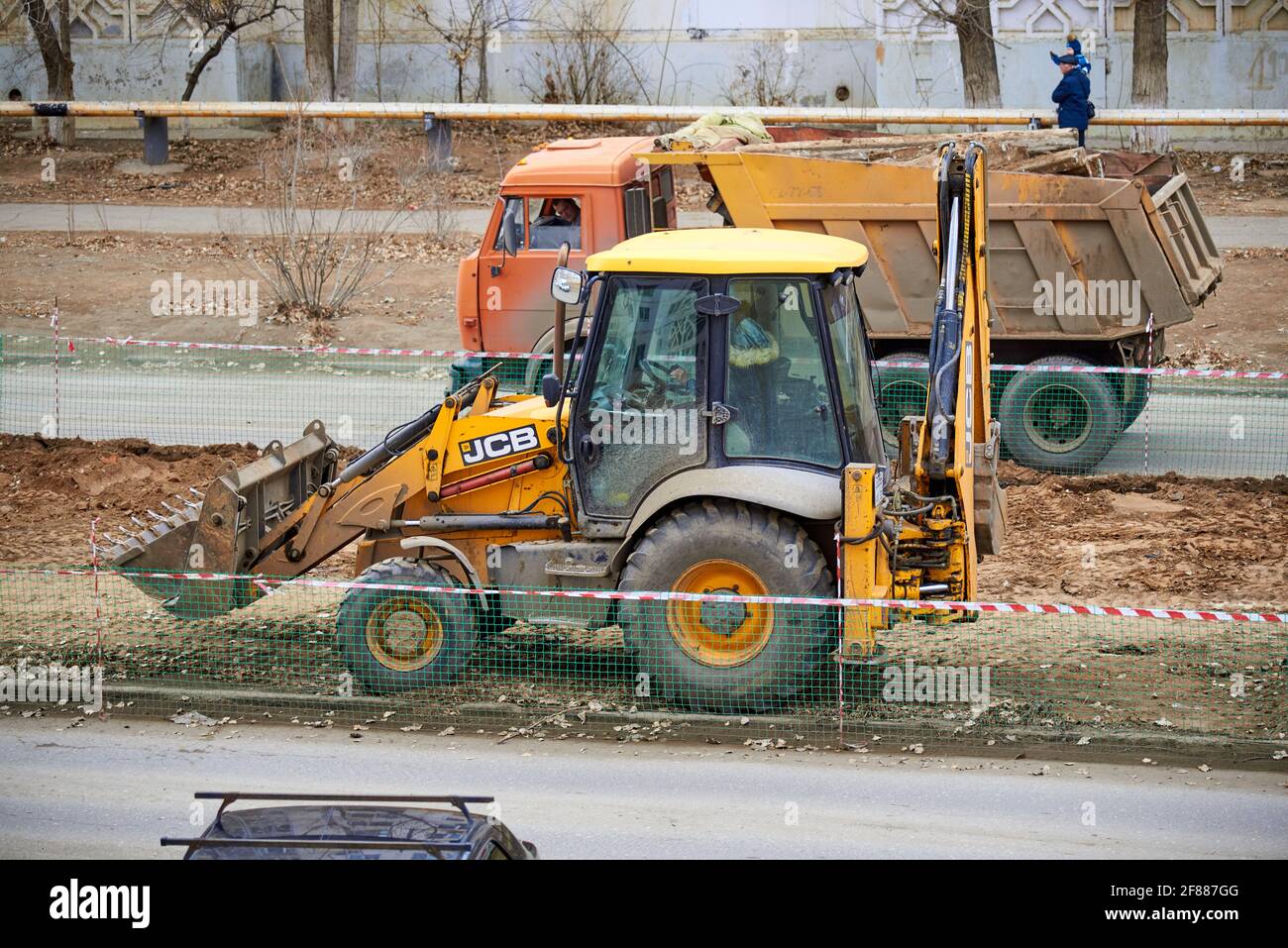 Astrakhan, Russia - 02.15.2021: JCB Backhoe Loader and Dump Truck Stock Photo