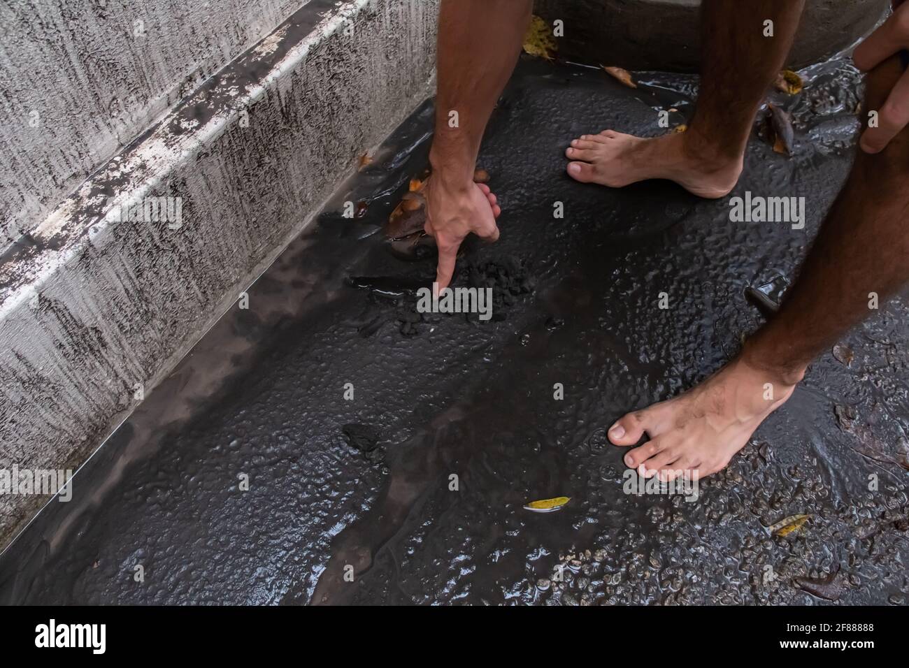 St. James, Barbados - April 11 2021: White man drags finger through wet volcanic ash from St. Vincent's Soufriere volcano eruption. Severe ash fall. Stock Photo