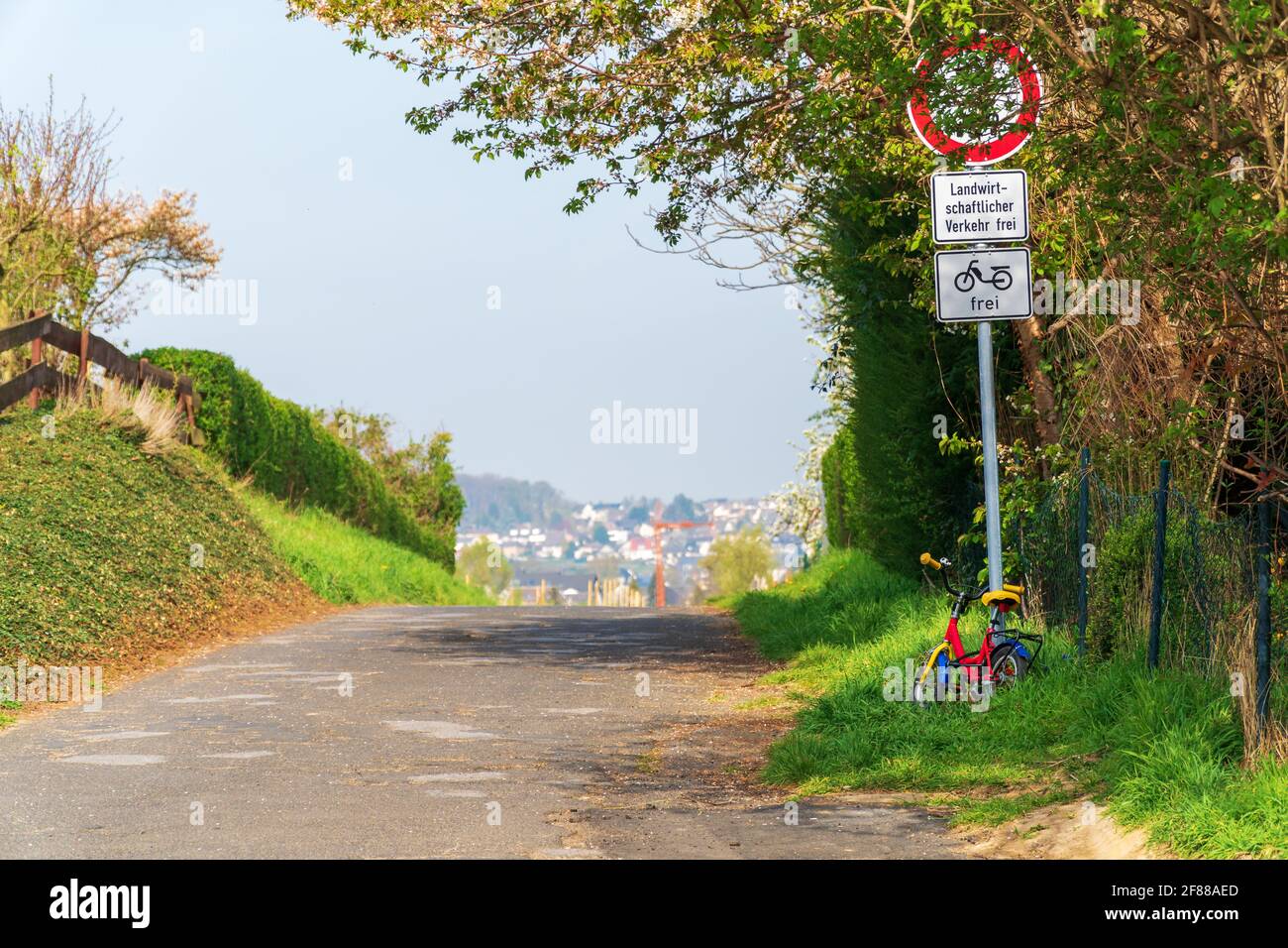Small child's bicycle parked at a traffic sign with German text that says: 'No through traffic. Agricultural traffic free. Mopeds allowed'. Stock Photo