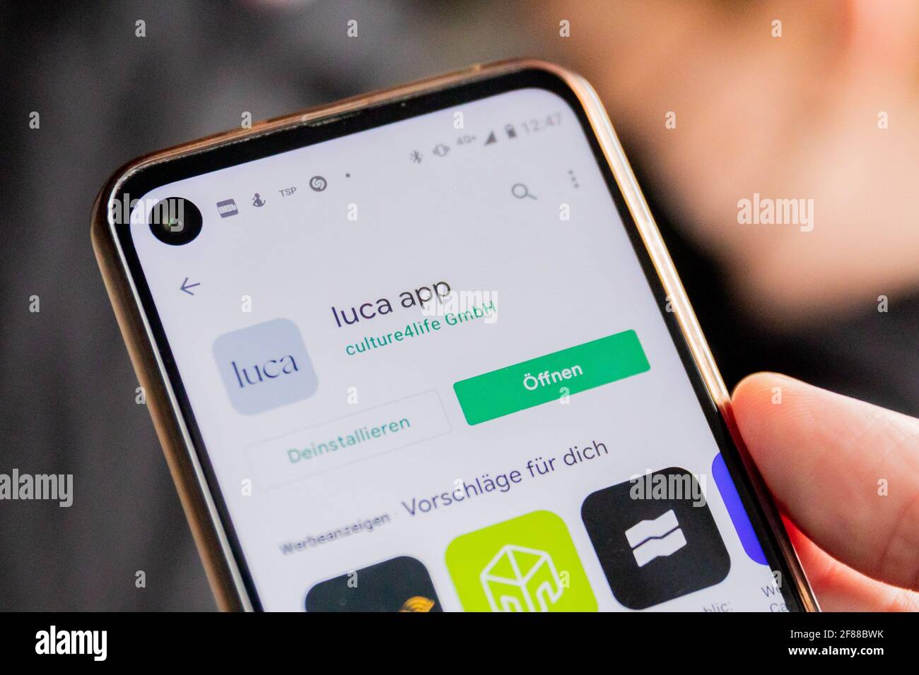 Berlin, Germany. 12th Apr, 2021. A customer holds up a smartphone with the Luca app to the camera at the entrance of a clothing store on Alexanderplatz. The app is used to provide data for possible contact tracing. Credit: Christoph Soeder/dpa/Alamy Live News Stock Photo