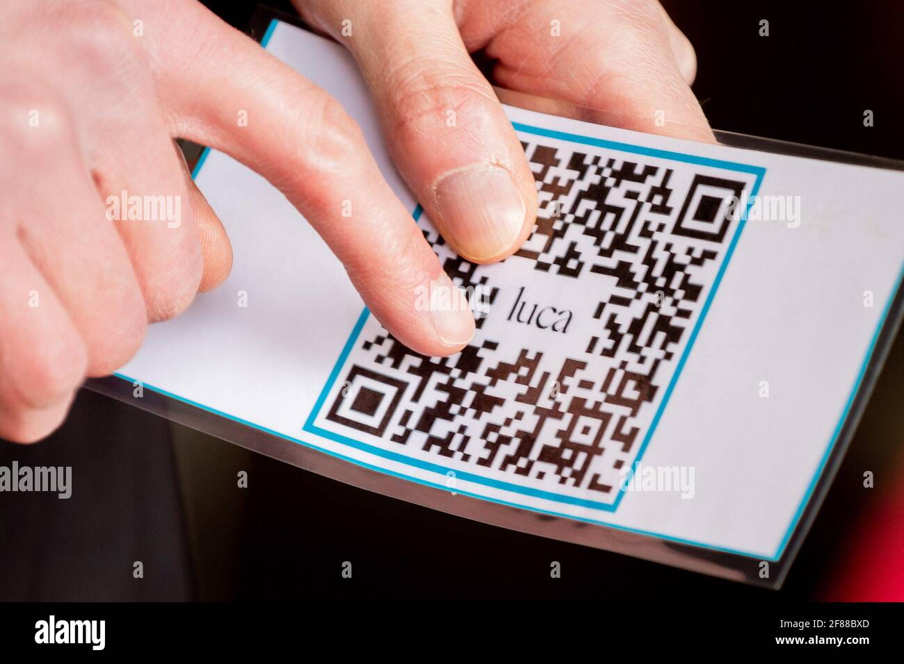 Berlin, Germany. 12th Apr, 2021. A security guard holds a check-in QR code from the Luca app at the entrance of a clothing store on Alexanderplatz. The app is used to provide data for possible contact tracing. Credit: Christoph Soeder/dpa/Alamy Live News Stock Photo