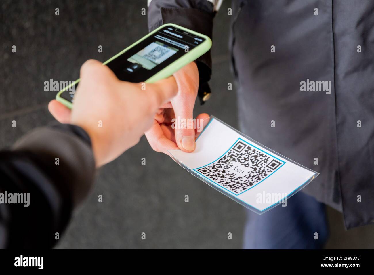 Berlin, Germany. 12th Apr, 2021. A person scans a QR code at the entrance of a clothing store at Alexanderplatz in front of a security guard using the Luca app. The app is used to provide data for possible contact tracing. Credit: Christoph Soeder/dpa/Alamy Live News Stock Photo