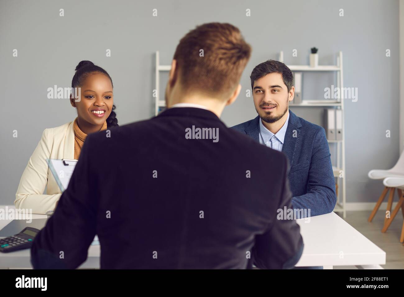 Happy young couple talking to bank manager, insurance advisor or mortgage broker Stock Photo