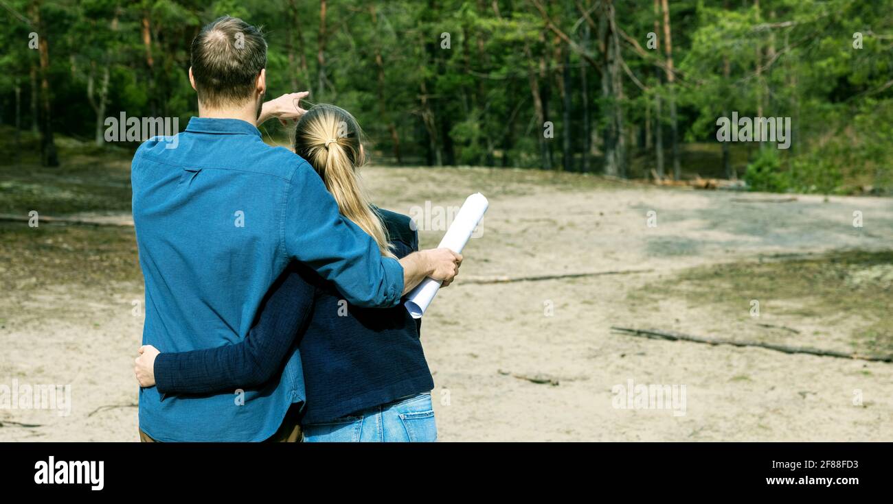 young couple choose a plot of land for dream house construction in forest. copy space Stock Photo