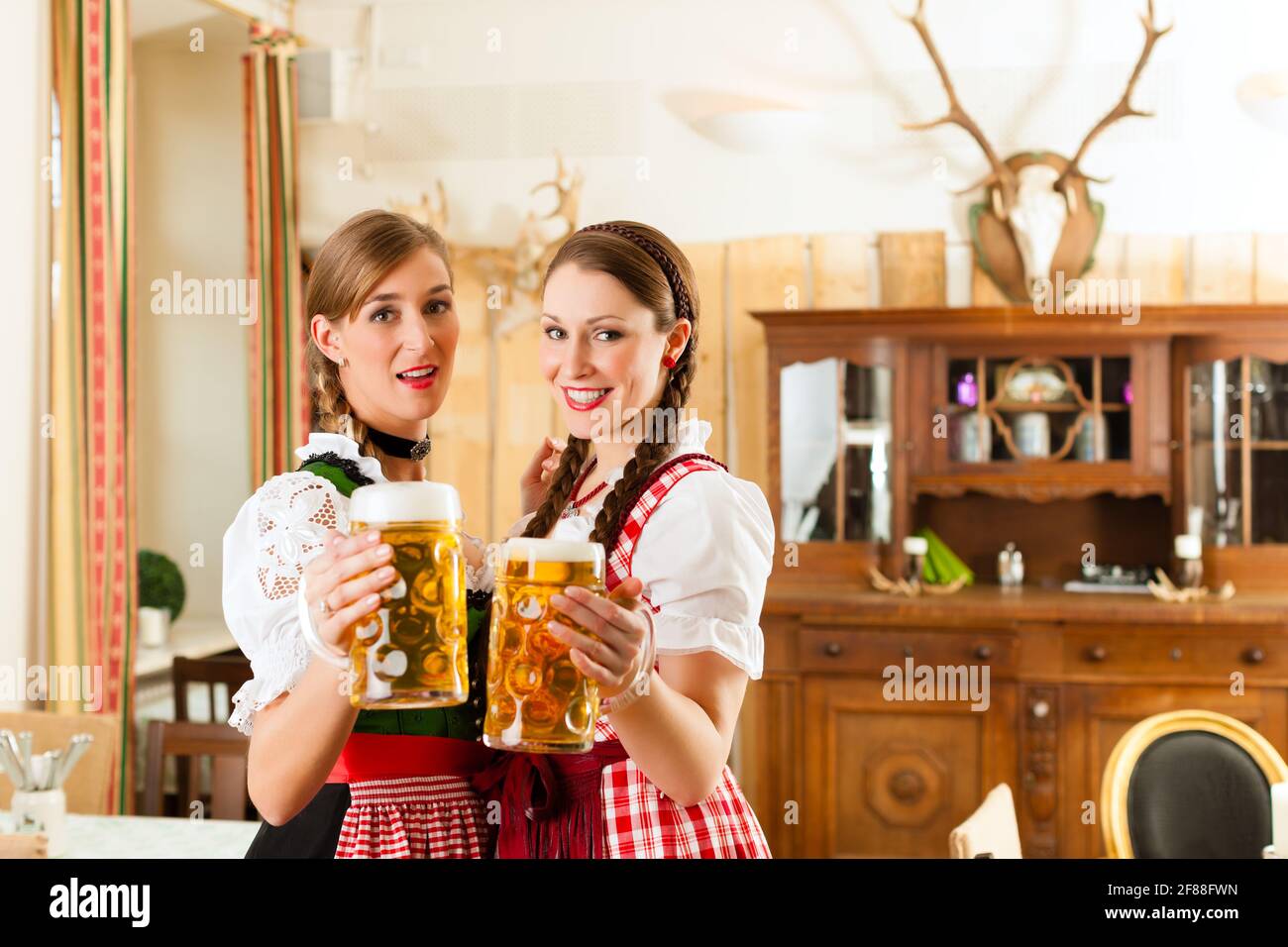 Two young women in traditional Bavarian Tracht in restaurant or pub ...