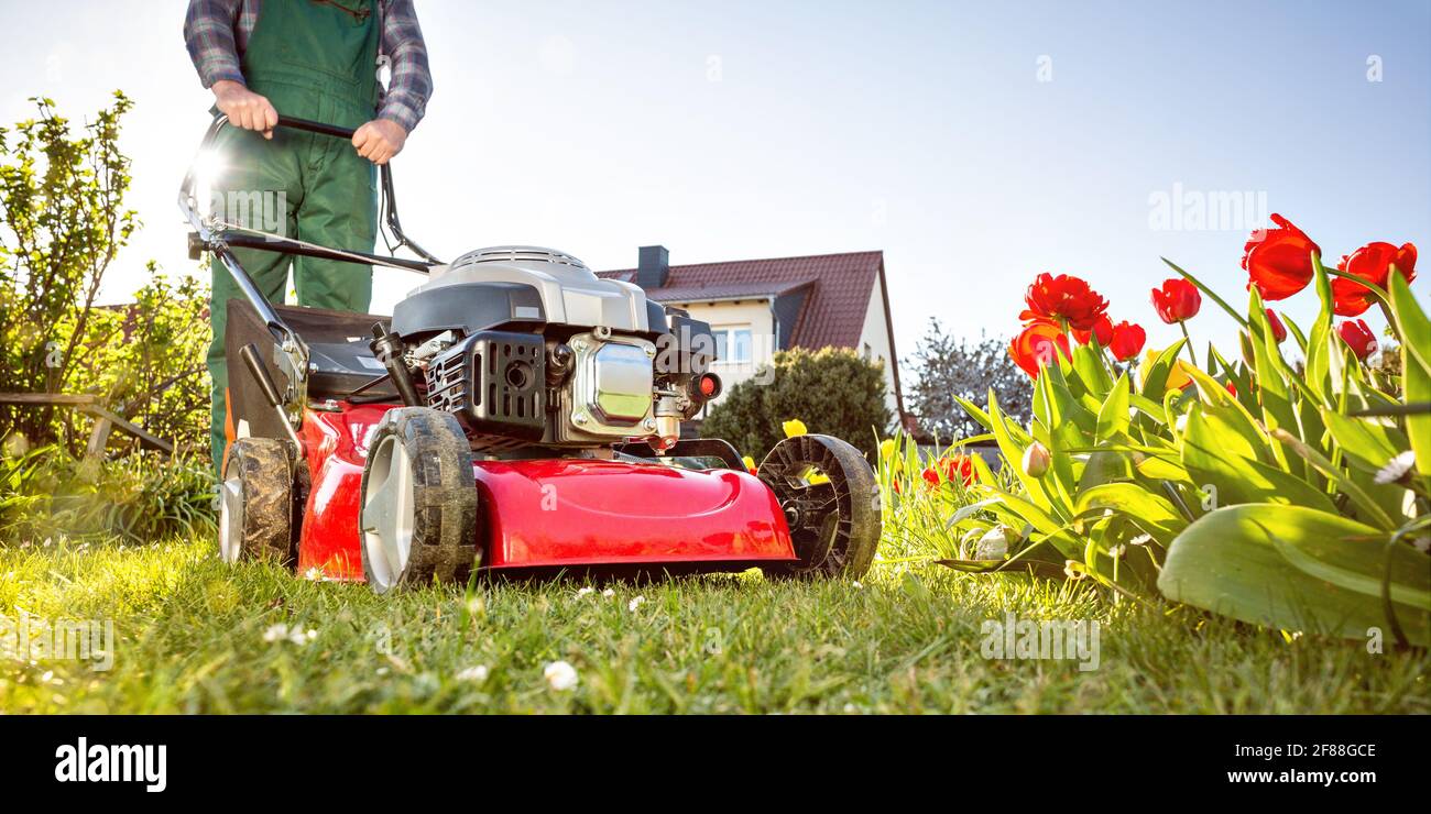 Lawn mower in a sunny garden at spring time Stock Photo