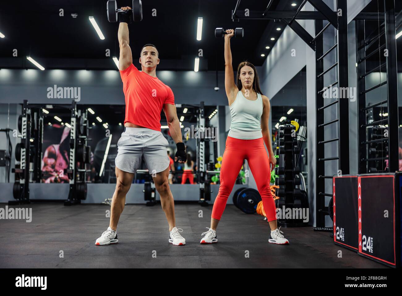 The fitness team does arm exercises with weights in the gym with a black base. With strong