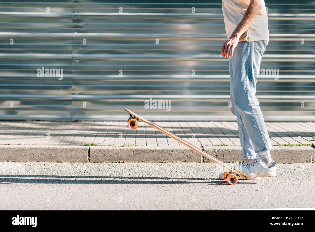 legs of an unrecognizable caucasian thin man lifting a skateboard with his feet Stock Photo