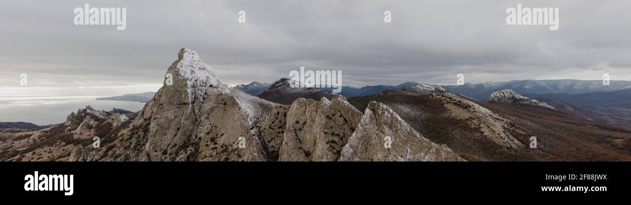 Panorama of mountain peaks in the snow with mountainous terrain sea and sky in the background. Stock Photo