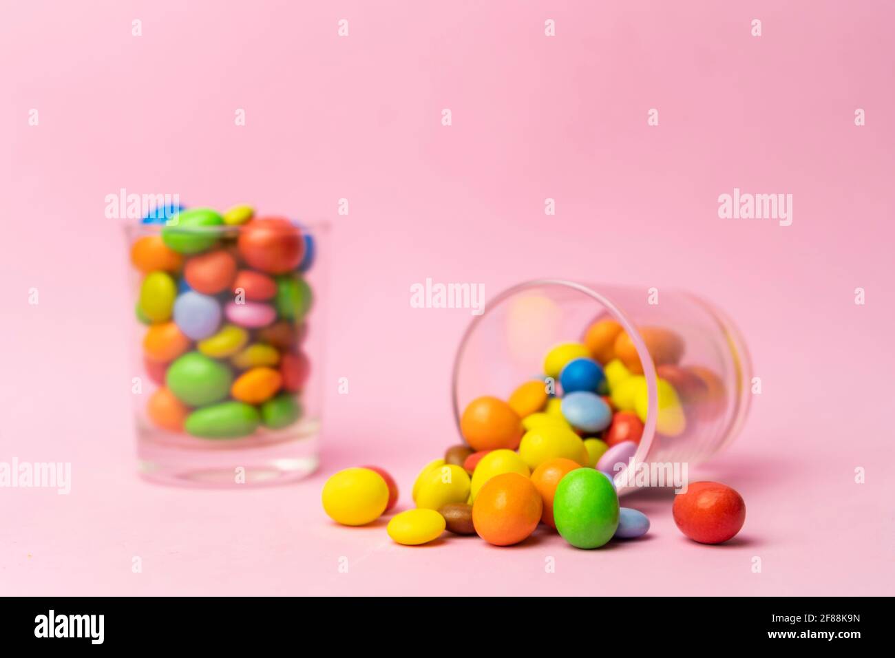 Multicolored chocolate candies in glass jar on blue vintage wooden background.Colorful sweets background concept with copy space for text. Stock Photo