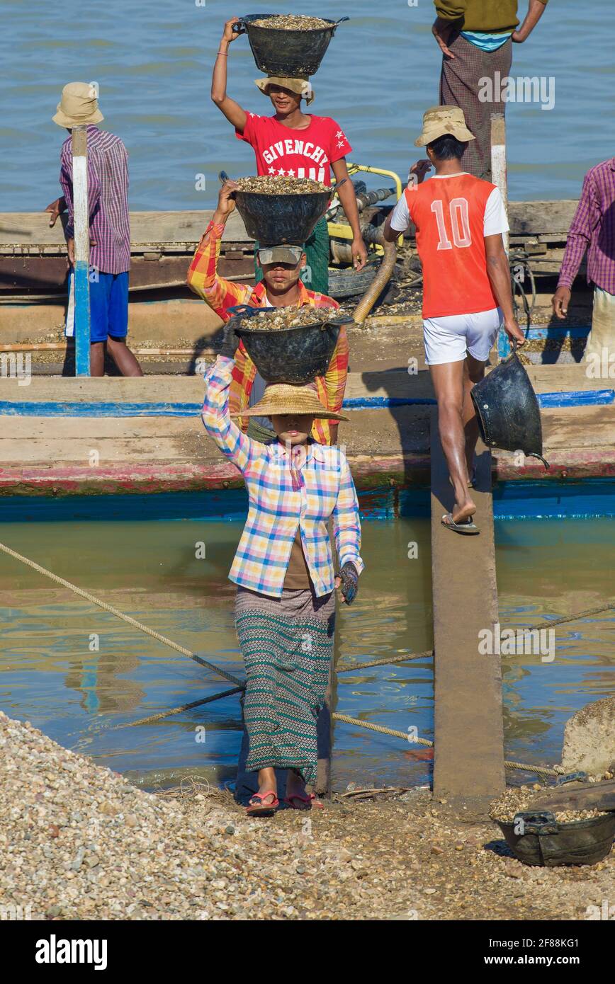 BAGAN, MYANMAR - DEC 23, 2016: Burmese unload boats with river gravel Stock Photo