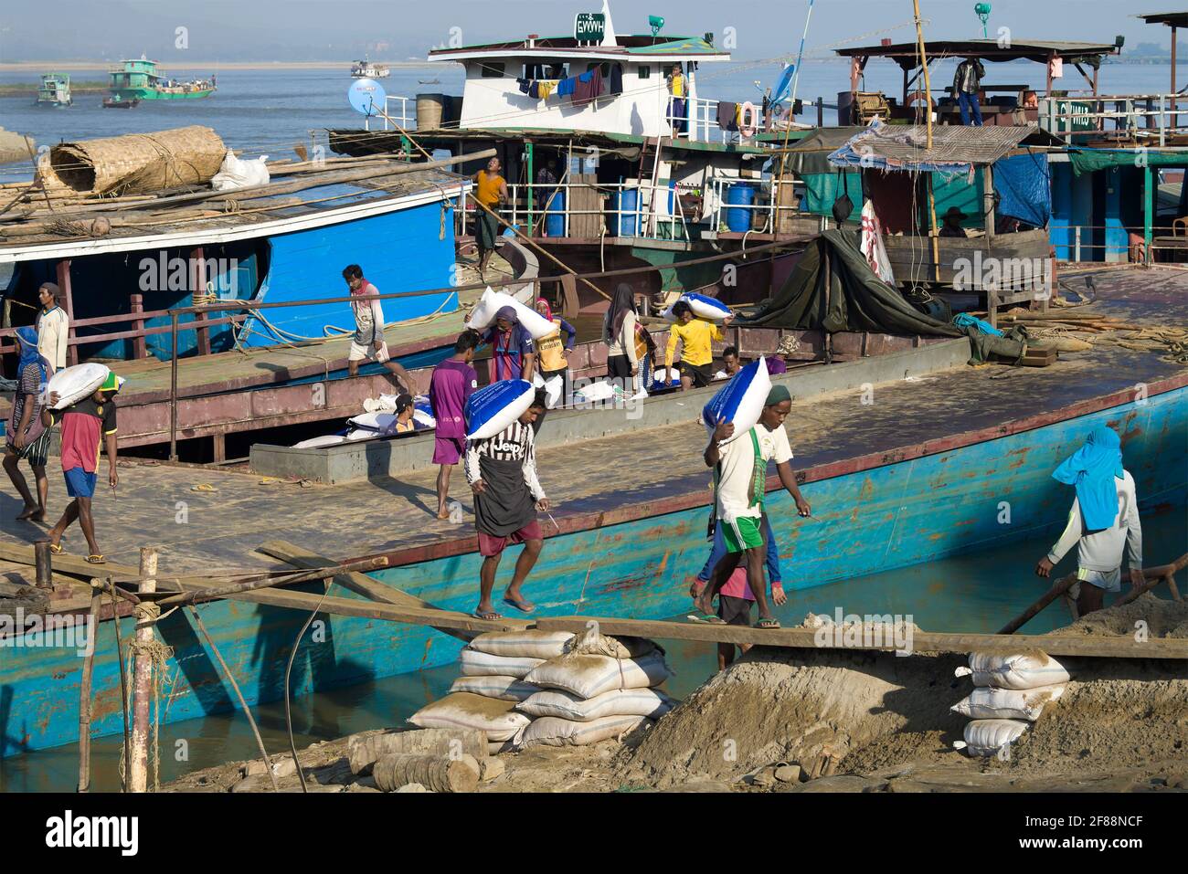MANDALAY, MYANMAR - DECEMBER 21, 2016: Unloading a barge in the river port Stock Photo