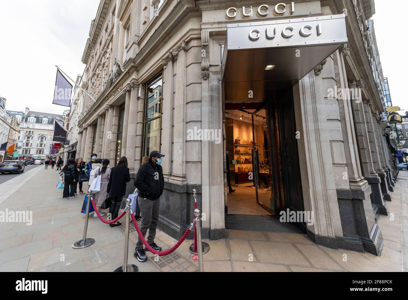 London, UK. 12 April 2021. People queue to enter the Gucci store in Old  Bond Street in Mayfair following the UK government's coronavirus roadmap  out of lockdown which allowed non-essential shops to