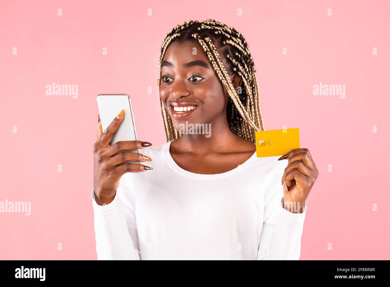 Excited black woman holding credit card and smartphone Stock Photo