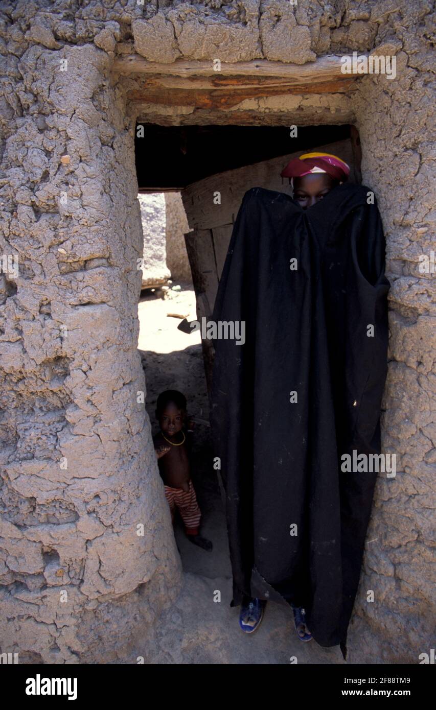 Woman covering her face and a small boy in a mud house in a rural village near Djenne, Mali Stock Photo