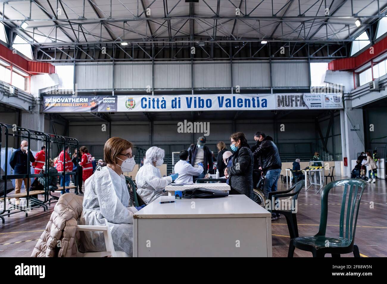 Doctors seen in the anamnesis area during the Mass vaccination. The elderly population in the Southern province of Vibo Valentia received the second recall of the anti COVID-19 vaccine Pfizer-BioNTech in the local sport palace (Palazzetto dello Sport). The local ASP (Provincial Sanitary Public Service), a team of the Italian Civil Protection, Italian Red Cross and local associations, continued the mass vaccination programme. Stock Photo