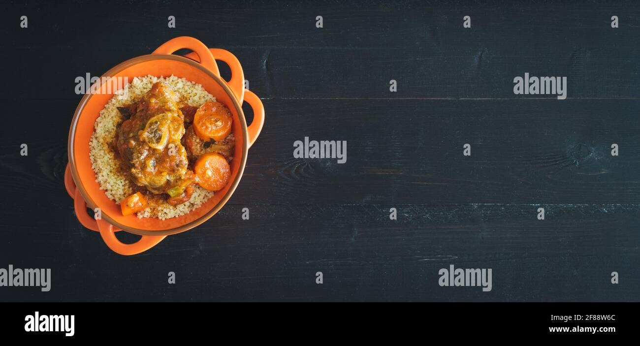 Casserole with lamb meat and couscous on black background. Copy space