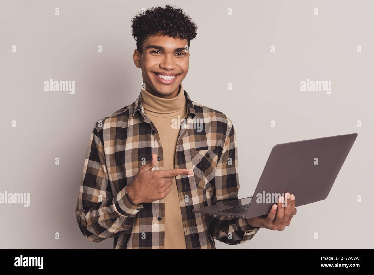 Photo of adviser guy direct forefinger hold netbook wear plaid shirt  turtleneck isolated grey color background Stock Photo - Alamy