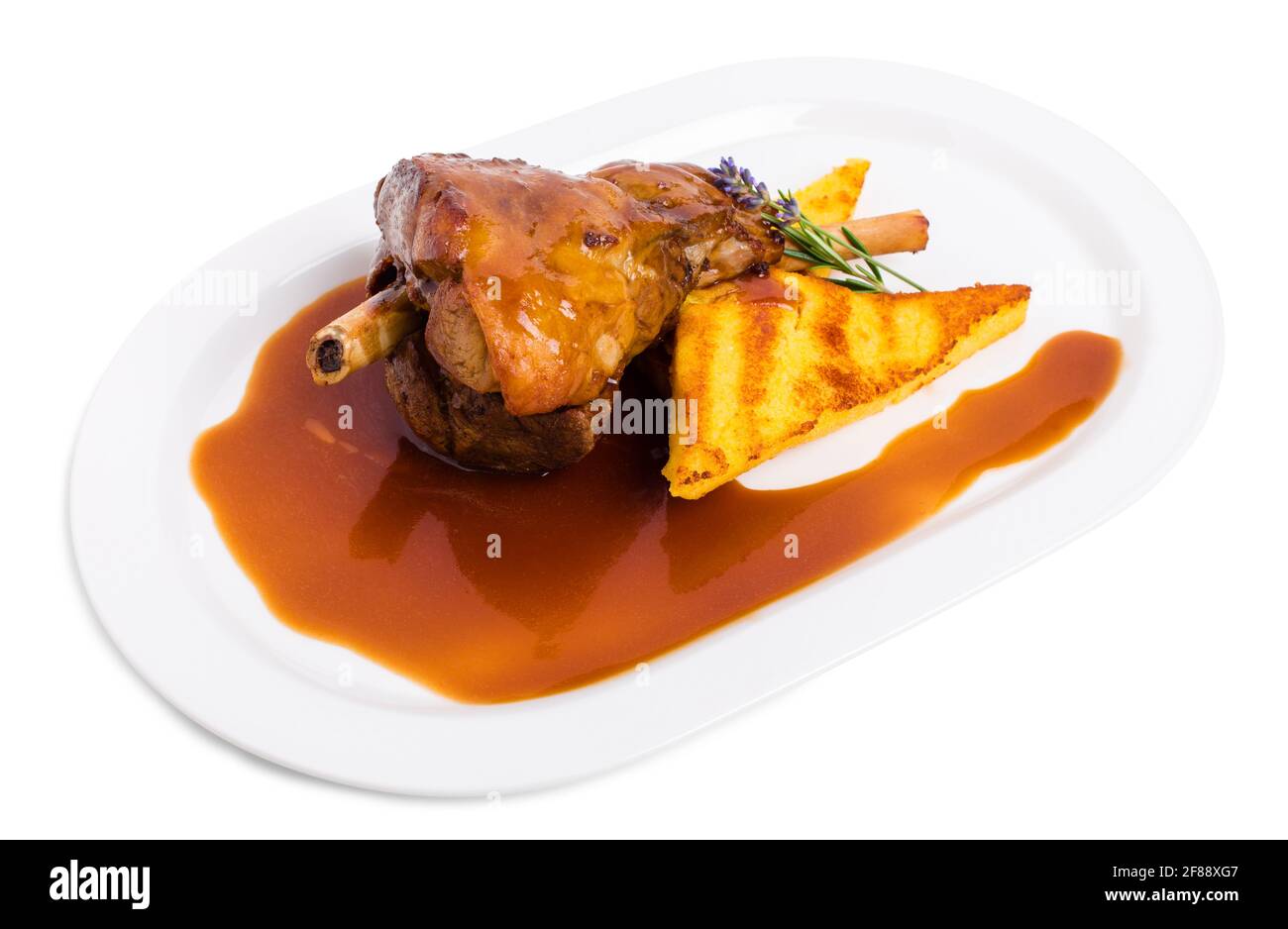 Fried lamb shank with polenta and covered with red sauce. Isolated on a white background. Stock Photo