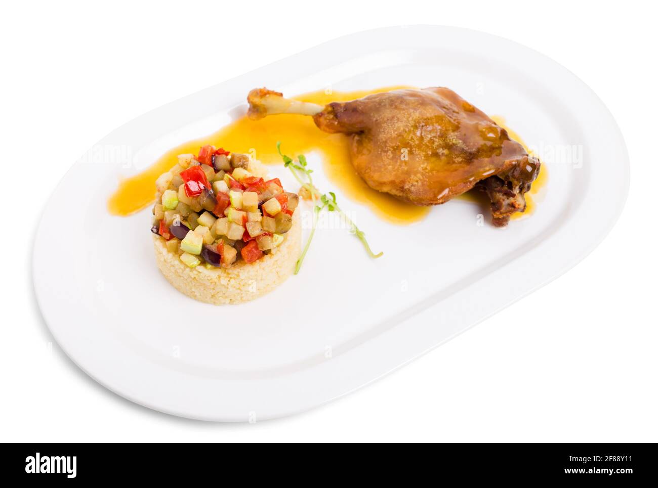 Duck leg confit with couscous and baked vegetables. Isolated on a white background. Stock Photo