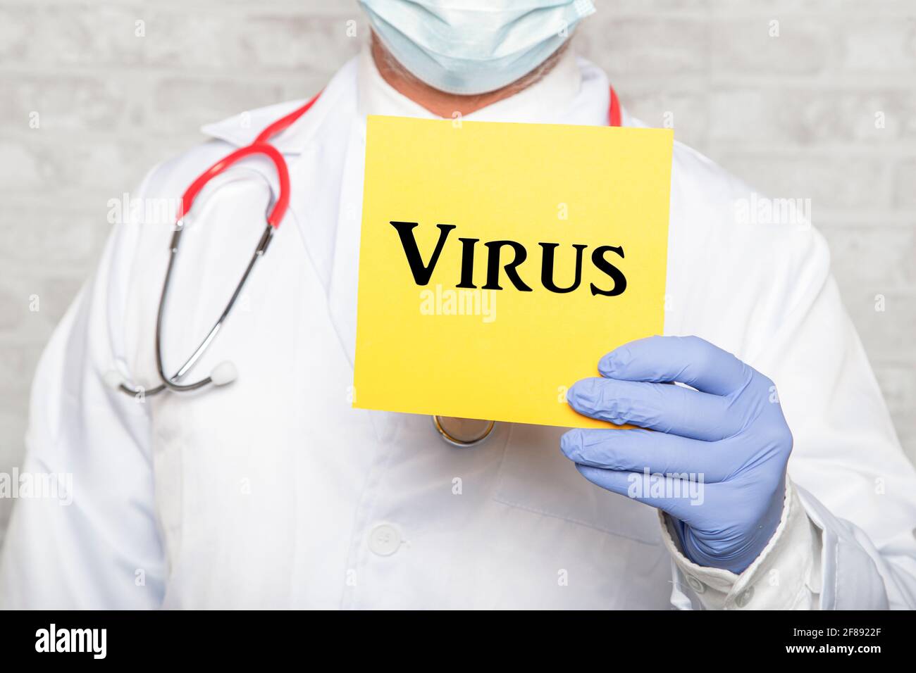 Portrait of doctor in gloves holding a sign with the text VIRUS Stock Photo