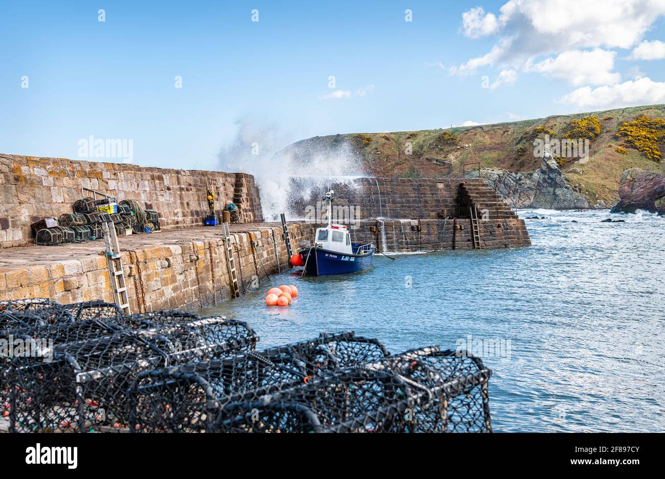 A fishing boat with a wave coming over the harbour wall at Cove Harbour