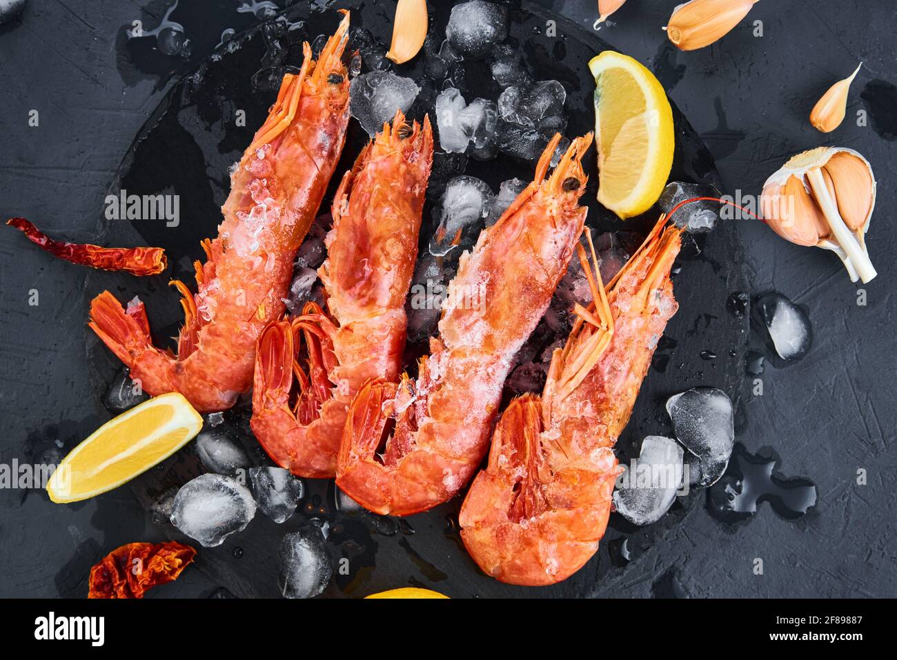 Fresh shrimps with lemon on dark background. Red raw prawns.Frozen seafood Stock Photo