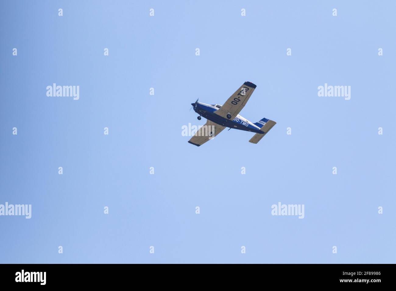 A portrait of a sport plane flying in a blue gradient sky. The small private aircraft has white wings and a blue bottom and tail. Stock Photo