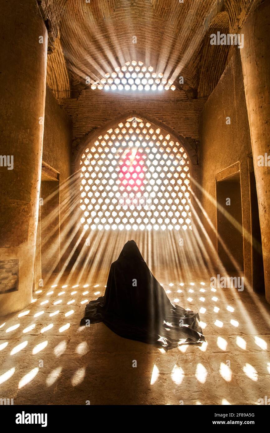 A muslim woman prays at Jameh Mosque of Isfahan. This is one of the oldest mosques still standing in Iran and It has been a Unesco World Heritage Site. Stock Photo