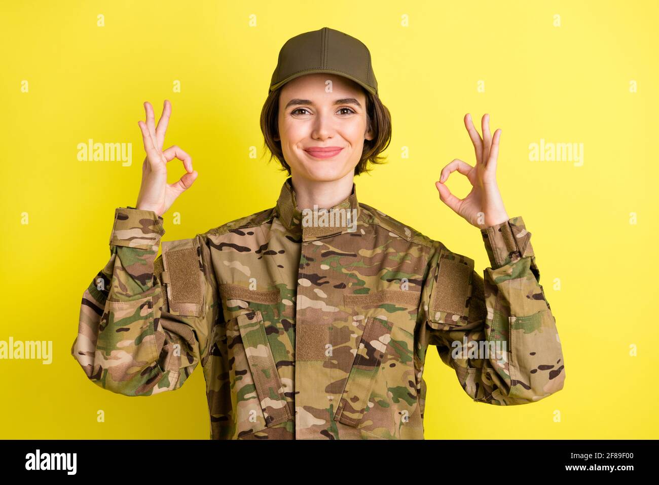 Portrait of charming lady two hands fingers show okey approval symbol isolated on yellow color background Stock Photo