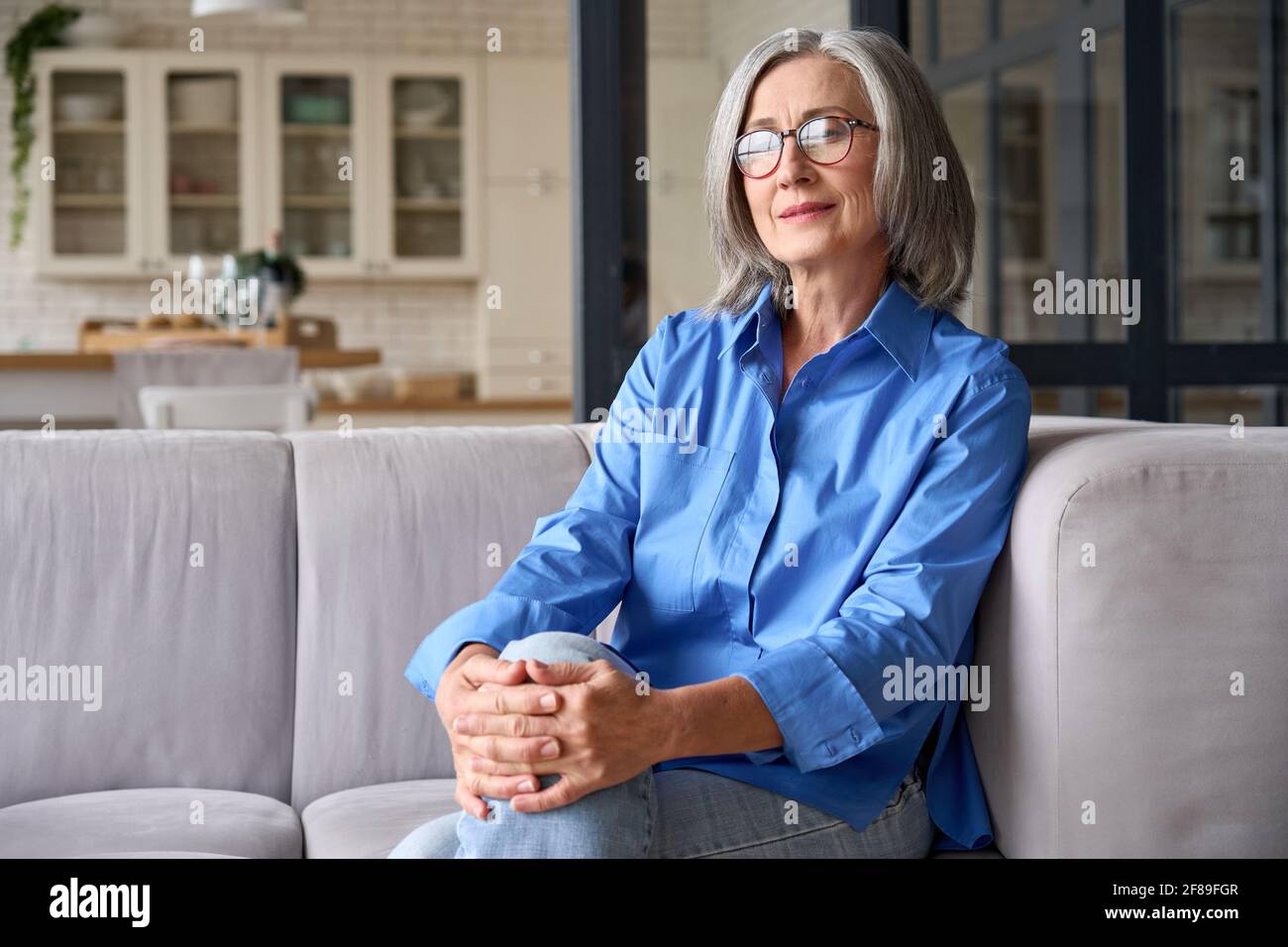 Mature smiling 60s woman portrait at home looking at camera. Stock Photo