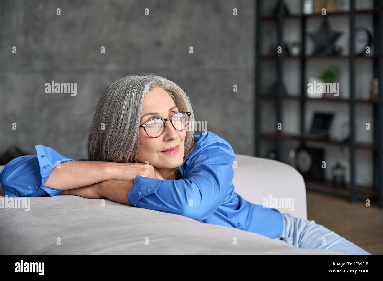 Senior mid age woman looking in window enjoying wellbeing and future vision. Stock Photo