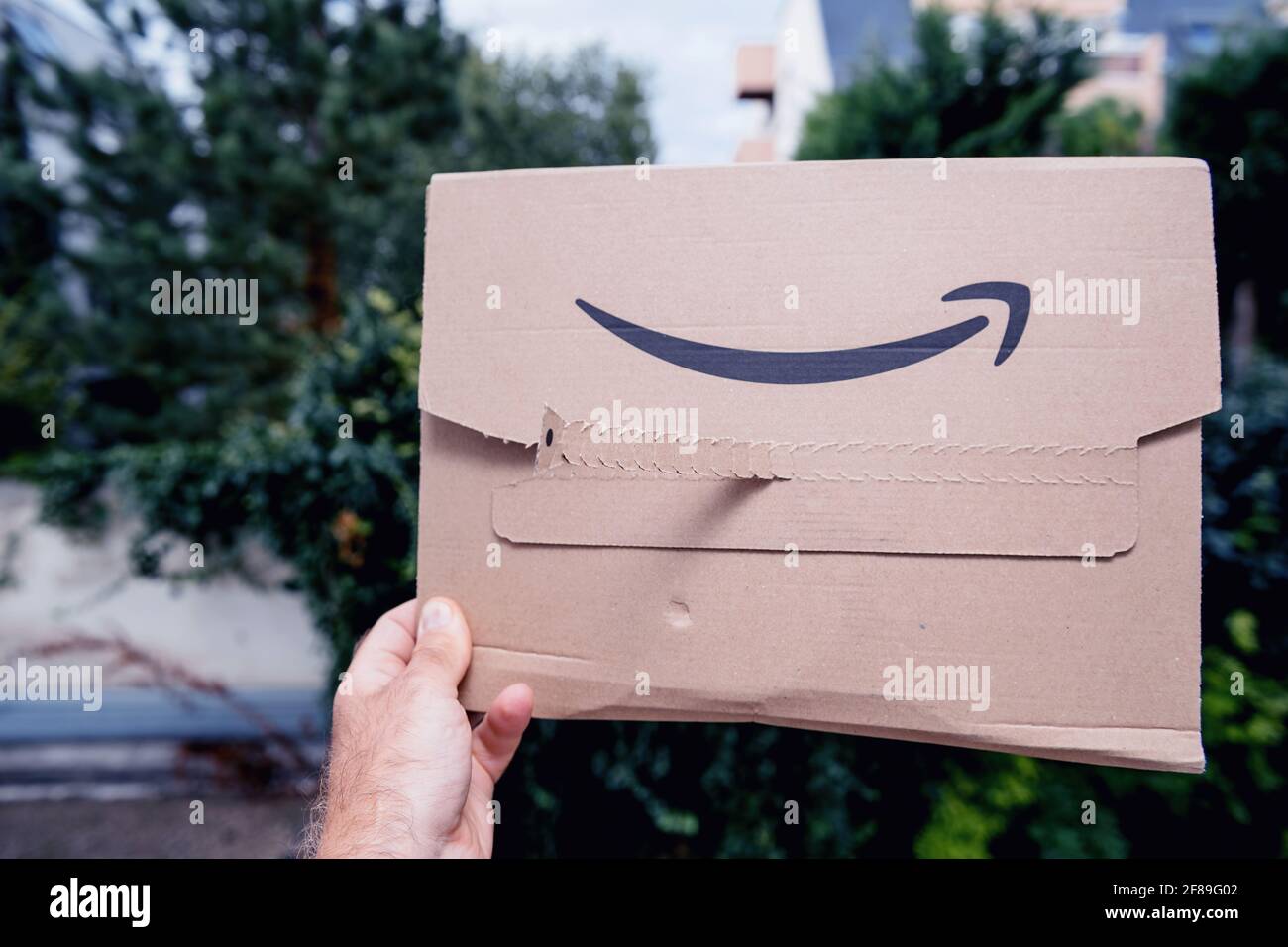Pov male hand holding new package of Amazon Prime cardboard package Stock Photo