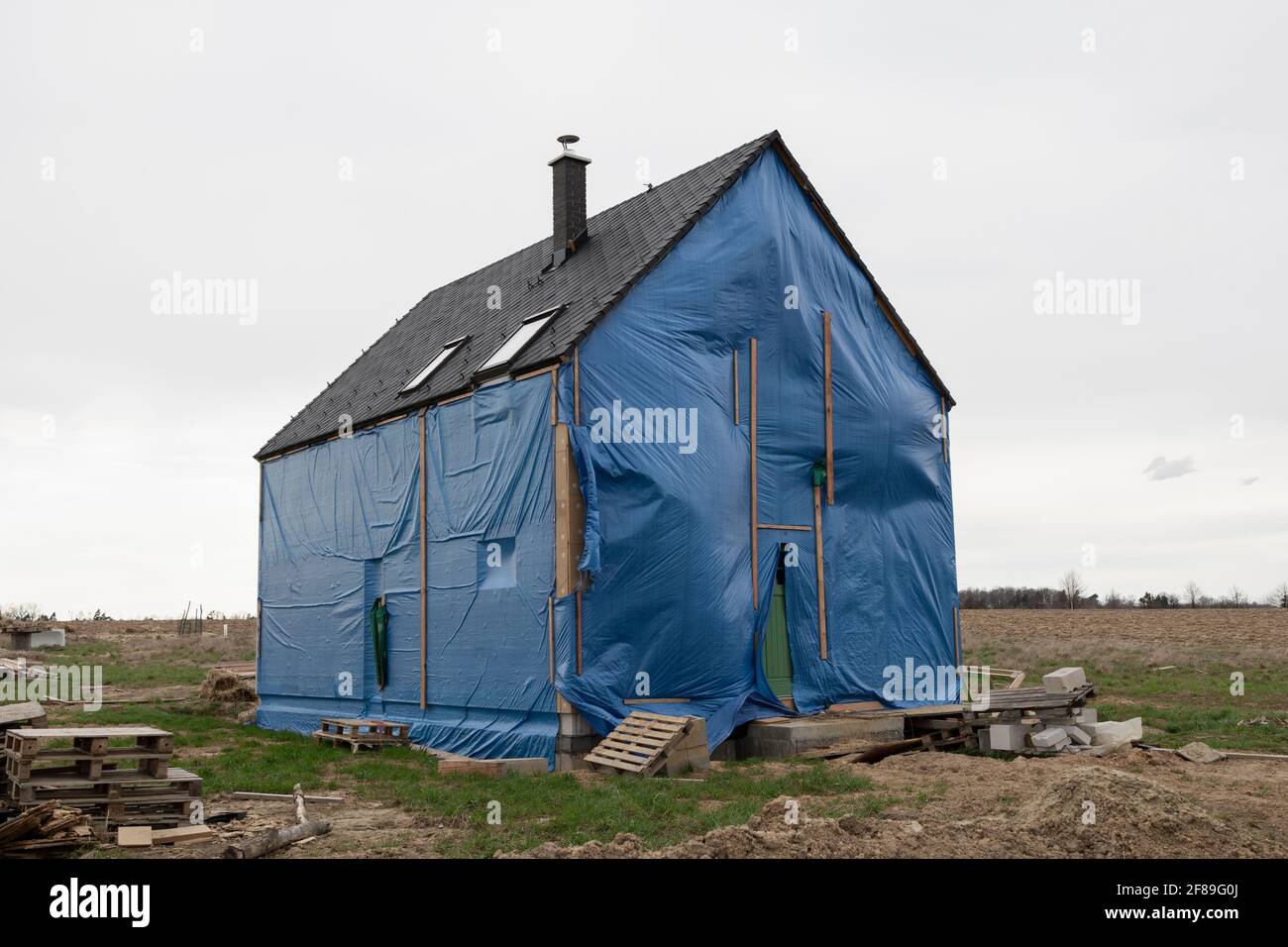 Construction and building site and family house. Unfinished building is covered by canvas and tarp. Stock Photo