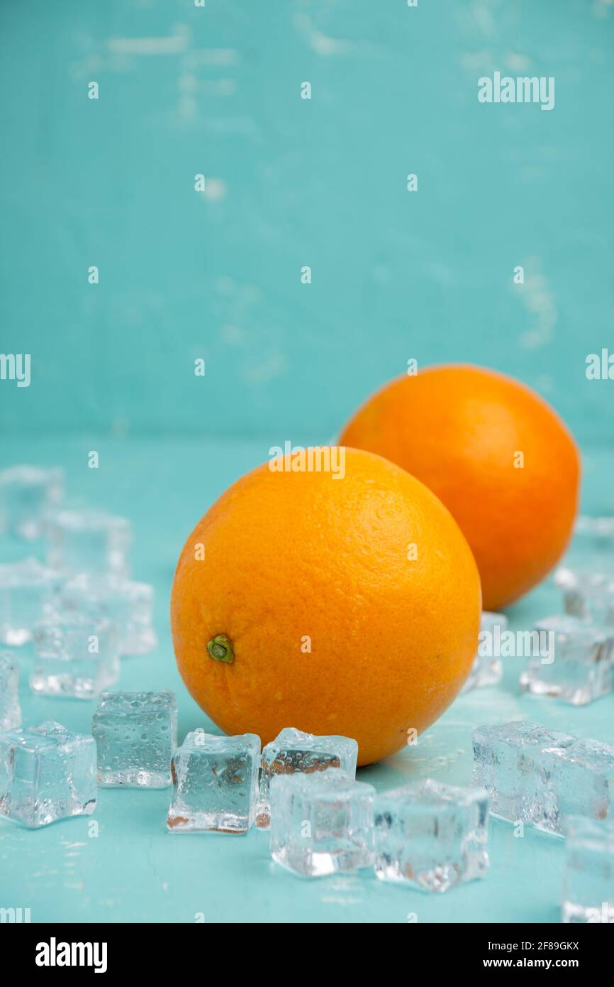 Top view of two oranges with ice on table and blue background, vertical, with copy space Stock Photo