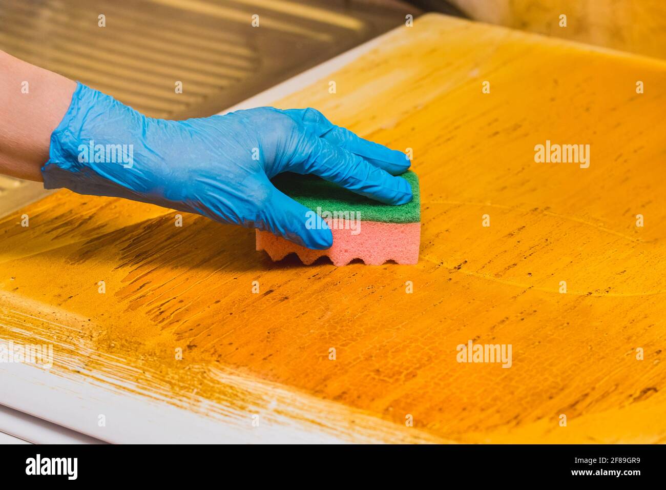 A woman's hand of a housewife in a household latex glove washes dirty