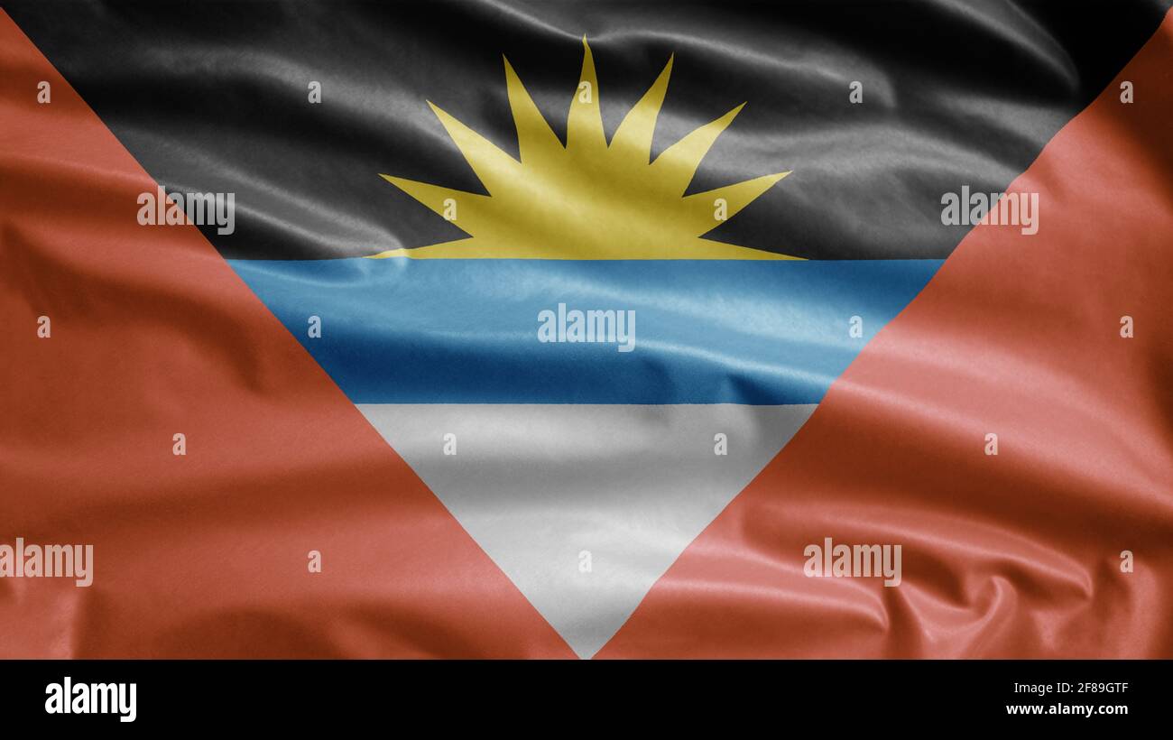 Antiguan and Barbudan flag waving in the wind. Close up of Antigua and Barbuda banner blowing, soft and smooth silk. Cloth fabric texture ensign backg Stock Photo