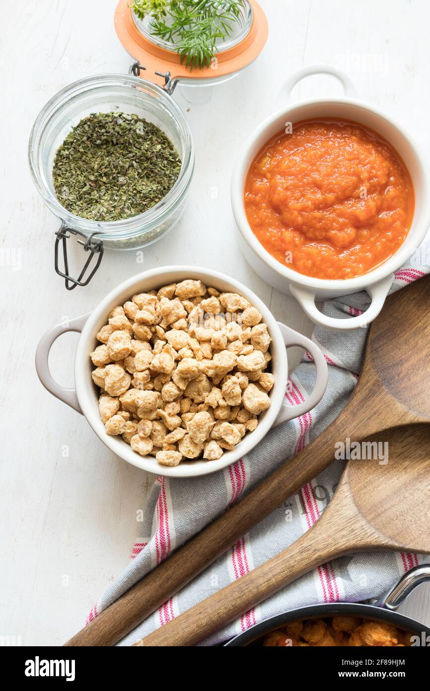 Two little casseroles with soya raw chunks and tomato sauce on a rustic background. Stock Photo