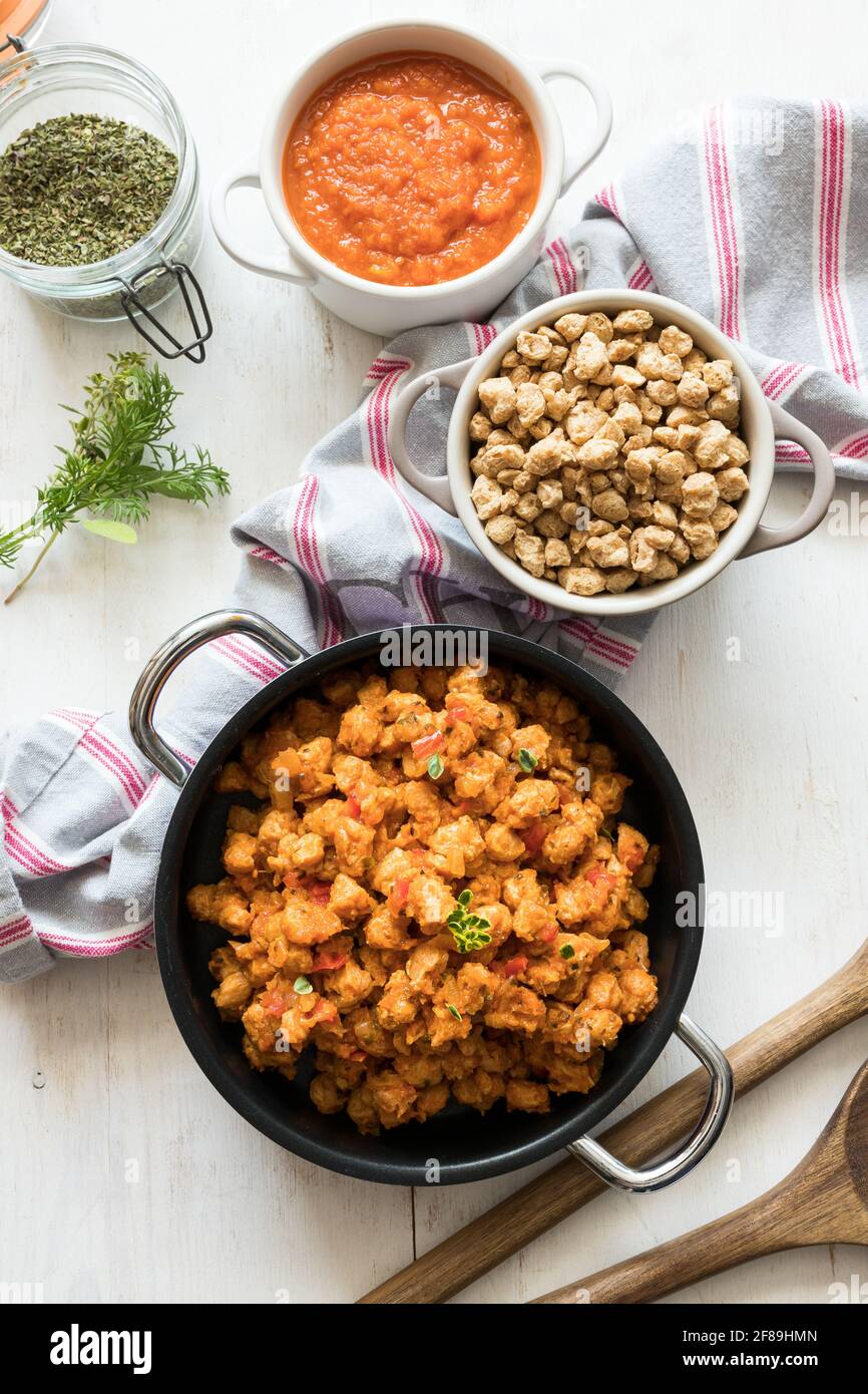 Healthy vegan scene composed of casseroles of bolognese soya meat, raw chunks of soy and tomato sauce. Stock Photo