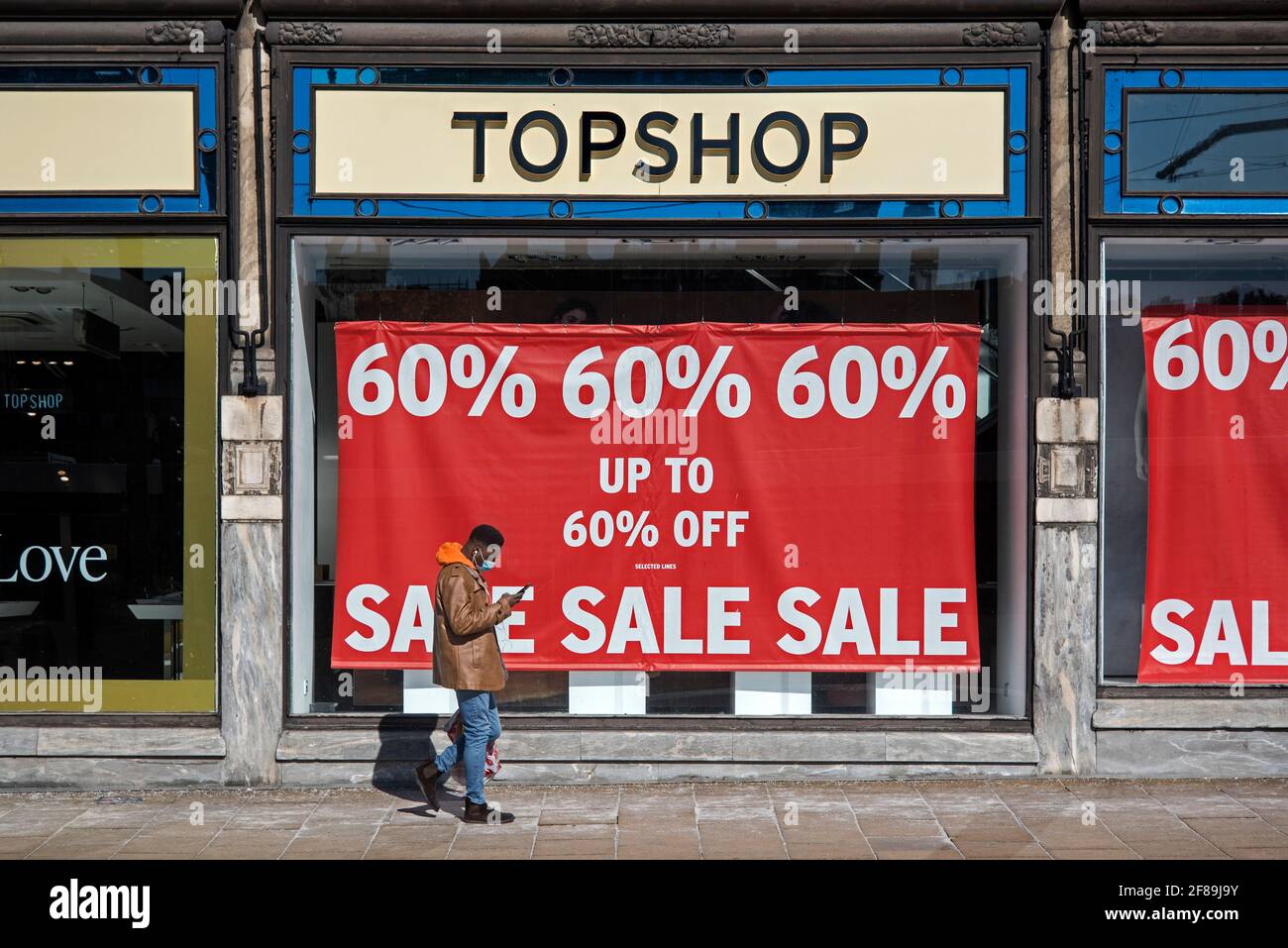 Man looking at his phone as he walks past the Sale sign on the now closed  Topshop on Princes Street, Edinburgh, Scotland, UK Stock Photo - Alamy