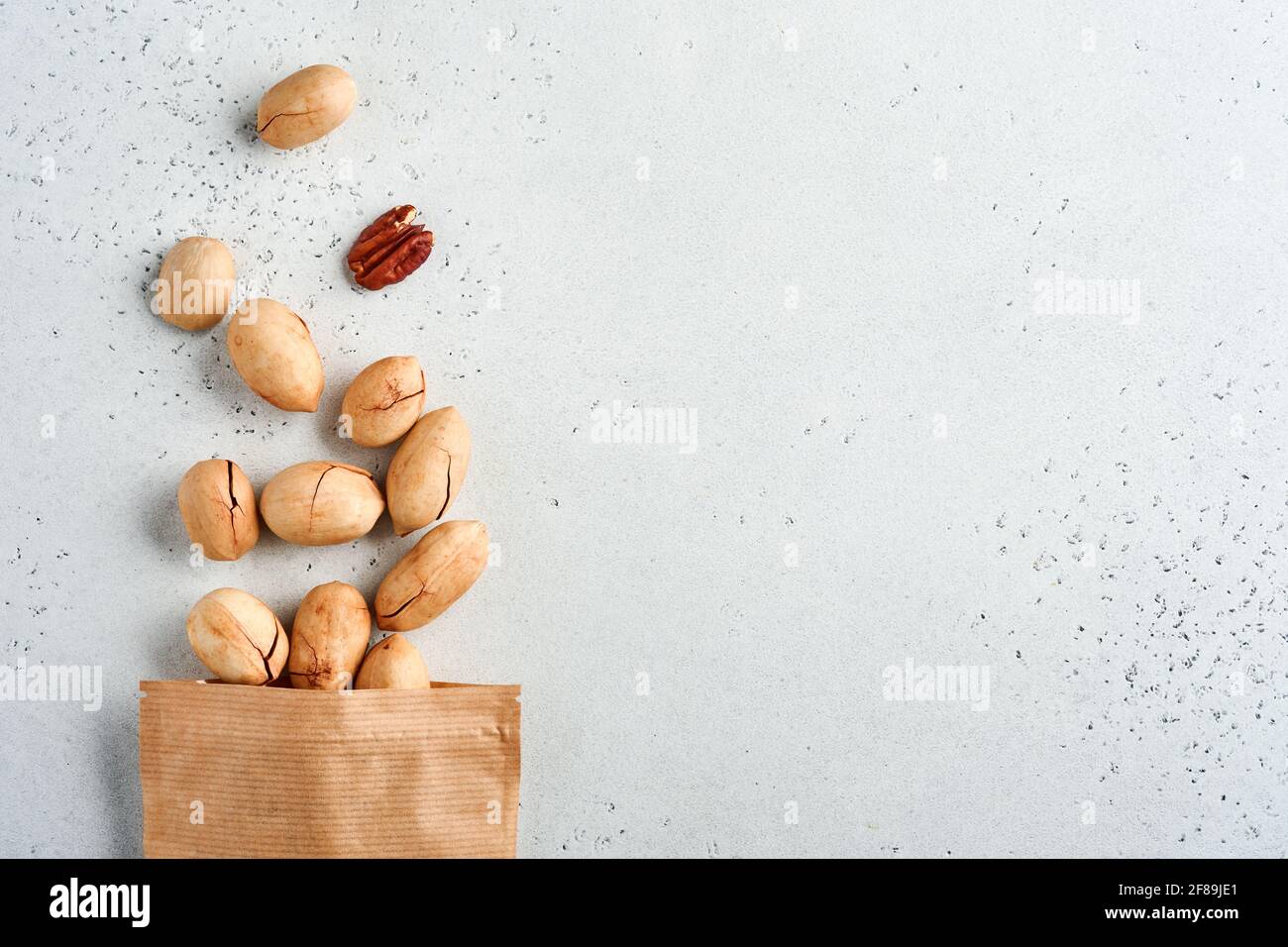 Nuts pecan in paper bag on white background with copy space. Snack
