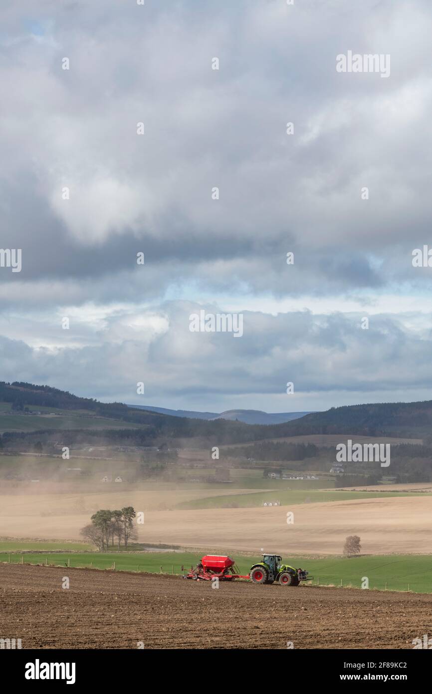 Wind Eroding Soil From Farmland in Aberdeenshire with a Tractor and Seed Drill Sowing Barley in the Foreground Stock Photo