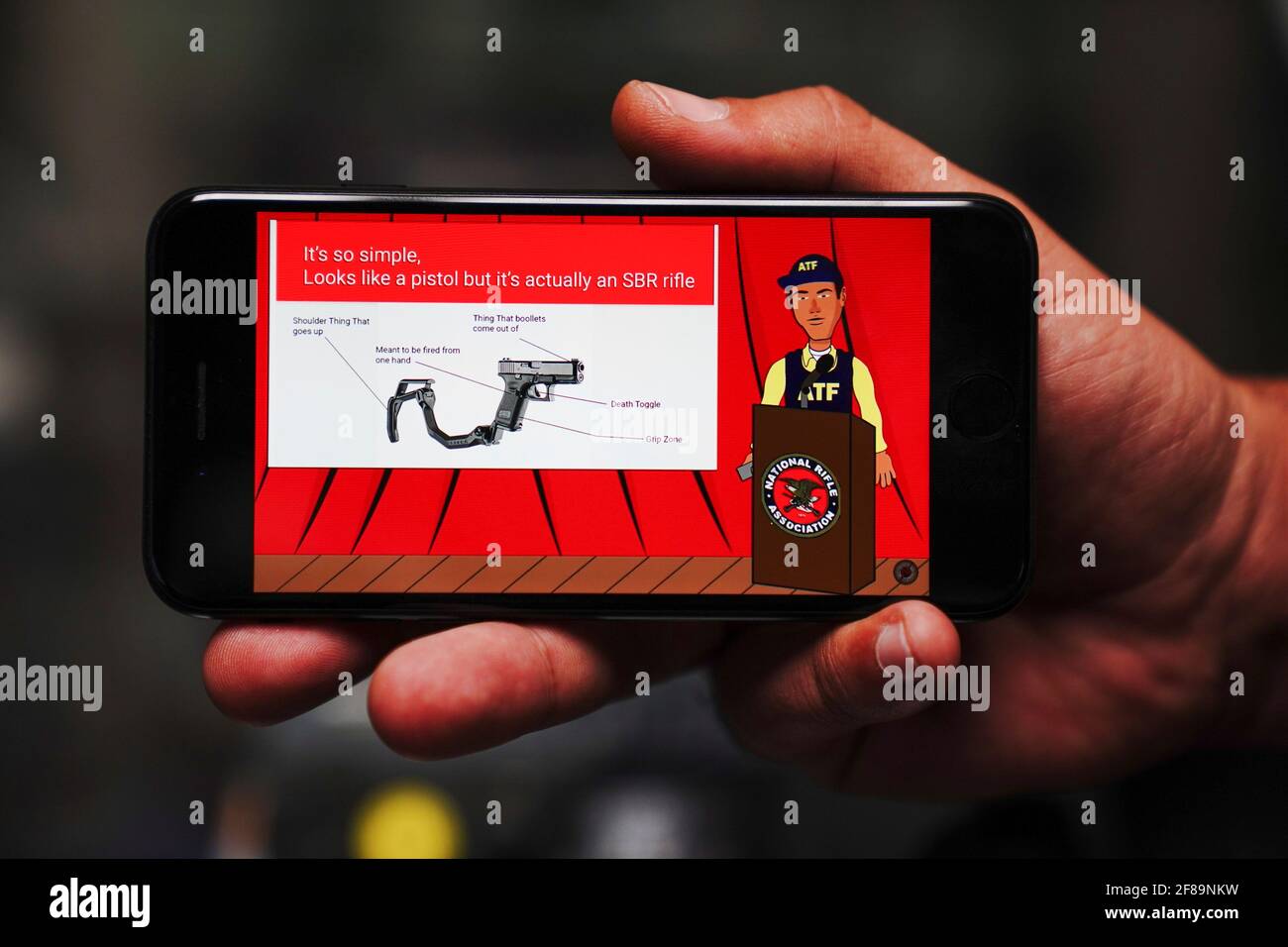 Dimitri Karras uses his mobile phone to show a YouTube video parodying the  Bureau of Alcohol, Firearms and Tobacco (ATF) and proposed Justice  Department restrictions on stabilizing braces and short-barreled rifles  (SBRs)
