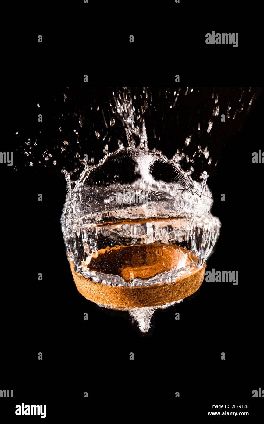 A drinks coaster splashes into water in black background Stock Photo