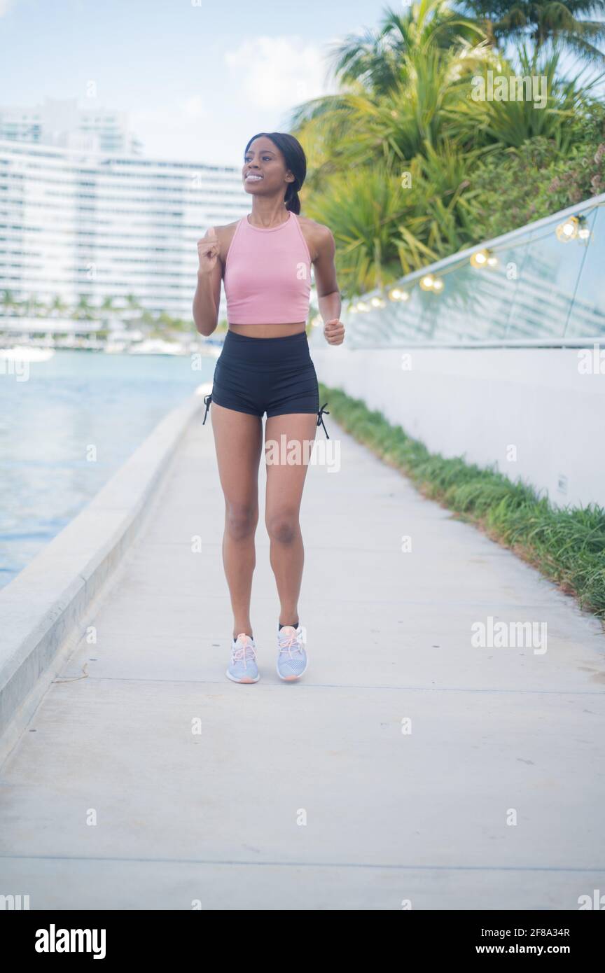Portrait of a Young African American Woman Jogging and Walking outside along the water Stock Photo