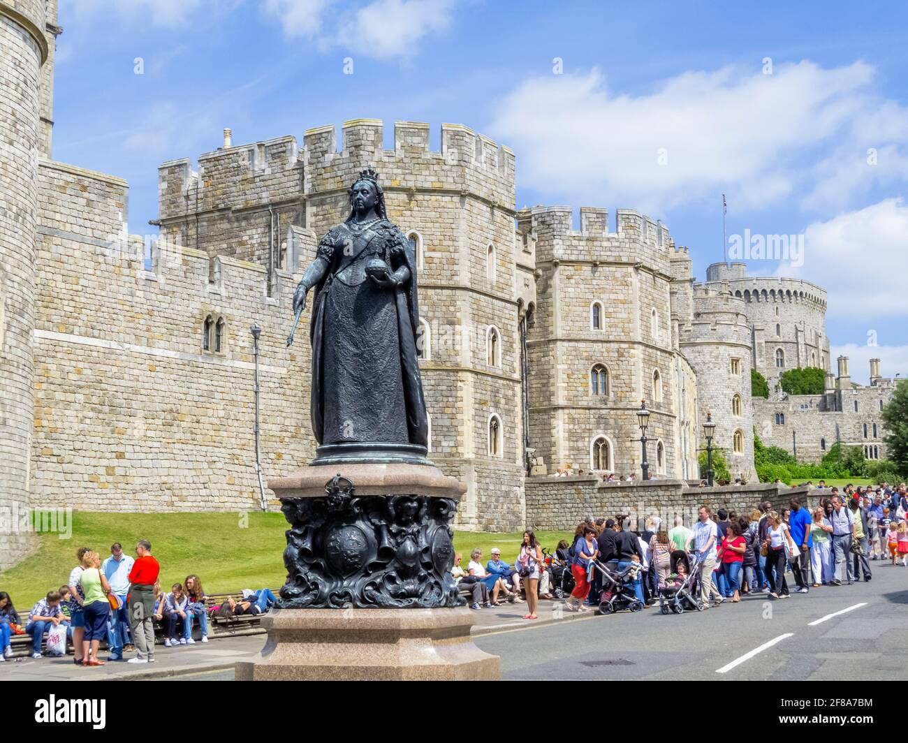 Crowds by the statue of Queen Victoria in Castle Hill outside the walls of Windsor Castle in Windsor, Berkshire, UK on a sunny day Stock Photo